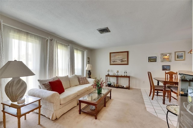 living room featuring light tile patterned floors, a textured ceiling, and visible vents