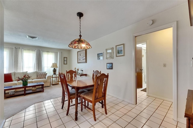 dining room with light colored carpet, visible vents, and light tile patterned flooring