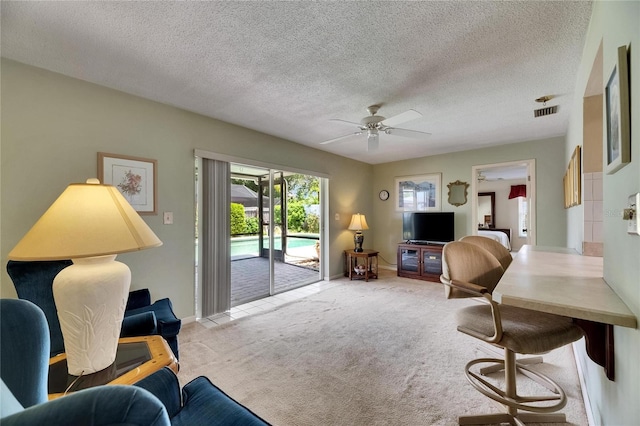 carpeted living room featuring a textured ceiling, ceiling fan, visible vents, and baseboards