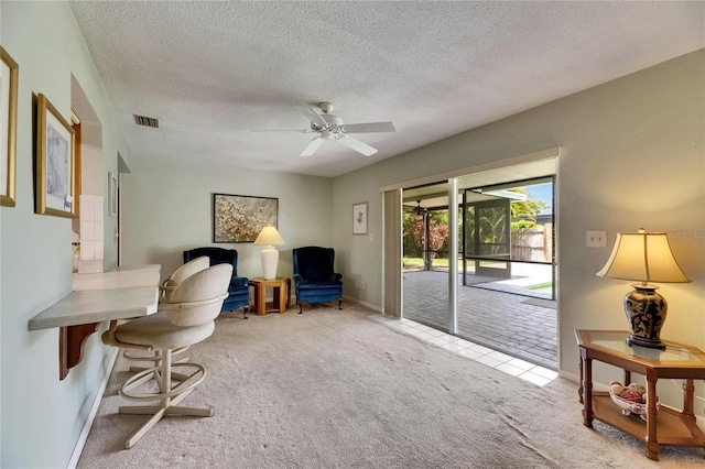 sitting room featuring carpet, ceiling fan, baseboards, visible vents, and a textured ceiling