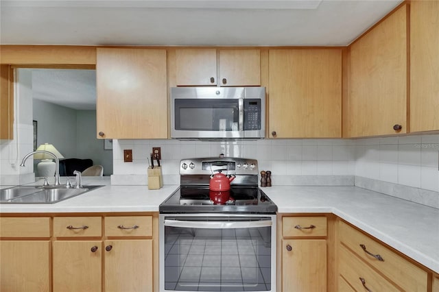kitchen featuring tasteful backsplash, a sink, light brown cabinets, stainless steel appliances, and light countertops