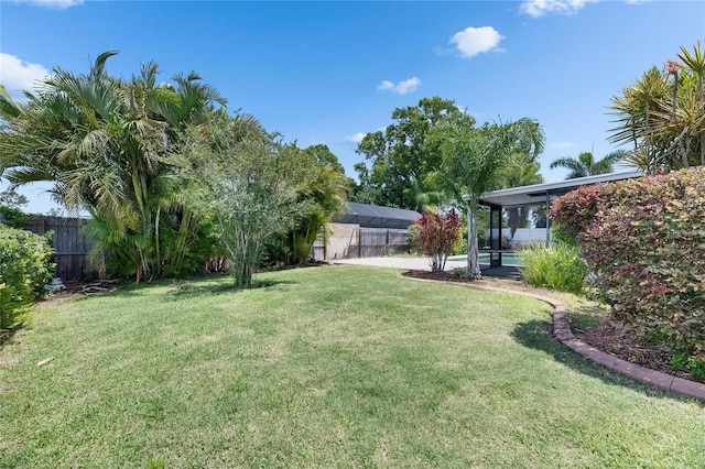 view of yard with fence and glass enclosure