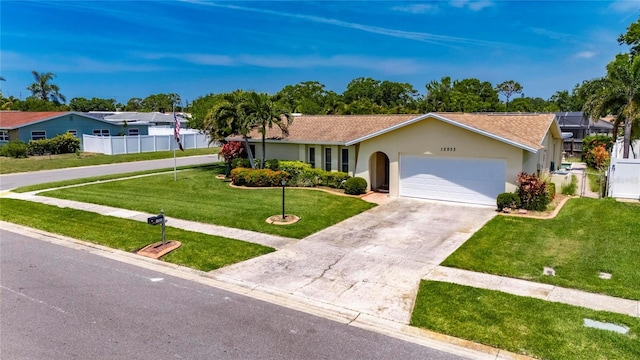 ranch-style house featuring driveway, fence, an attached garage, stucco siding, and a front lawn