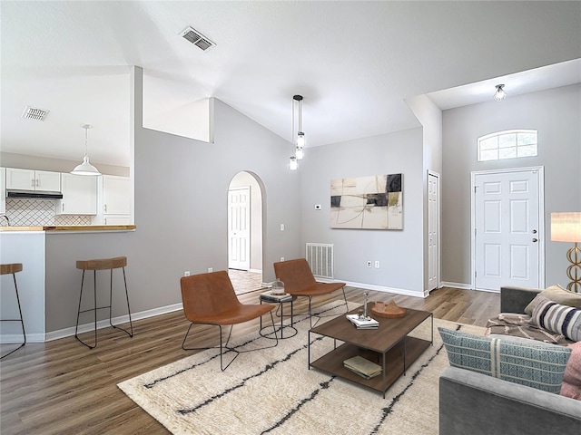 living room with visible vents, arched walkways, and wood finished floors