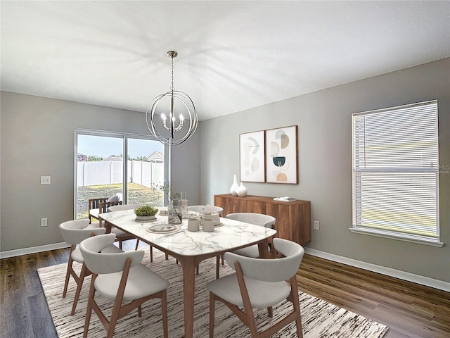 dining space featuring dark wood-type flooring, a notable chandelier, and baseboards