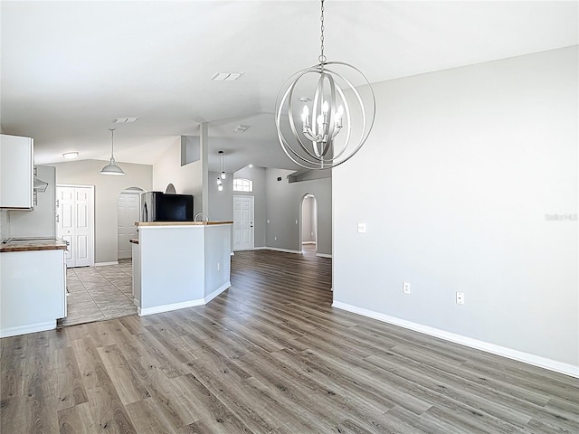 kitchen featuring light wood-style floors, a chandelier, baseboards, arched walkways, and vaulted ceiling