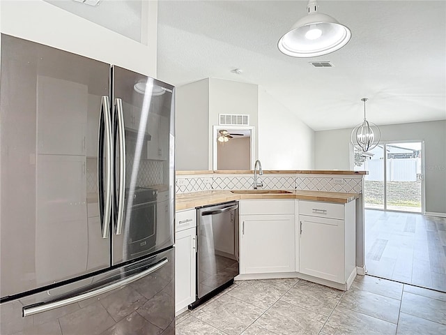 kitchen featuring stainless steel appliances, backsplash, a sink, visible vents, and lofted ceiling