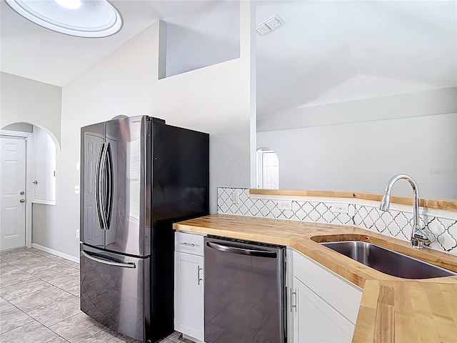 kitchen with lofted ceiling, a sink, appliances with stainless steel finishes, visible vents, and butcher block countertops