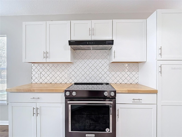 kitchen featuring electric stove, under cabinet range hood, wooden counters, backsplash, and white cabinetry