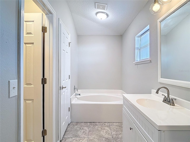 full bathroom with a garden tub, a textured ceiling, visible vents, and vanity