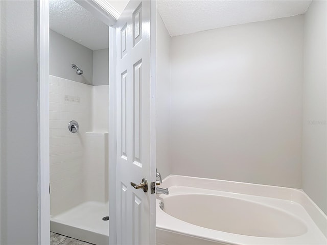 bathroom featuring a bath, a textured ceiling, and a shower