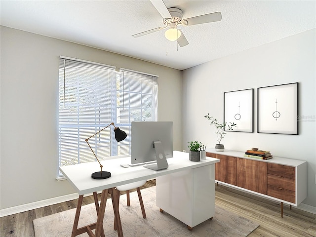 office space featuring a ceiling fan, baseboards, a textured ceiling, and light wood-type flooring