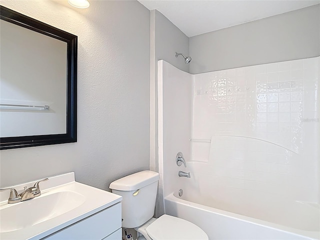 bathroom with toilet, shower / washtub combination, a textured wall, and vanity