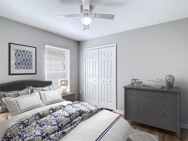 bedroom featuring baseboards, wood finished floors, ceiling fan, and a closet