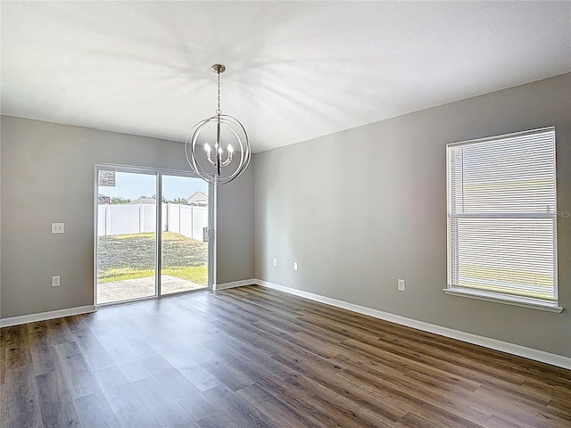 empty room featuring dark wood finished floors, baseboards, and a notable chandelier