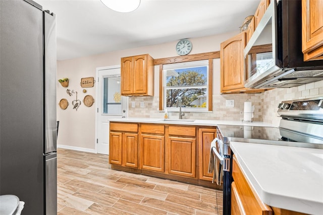 2134 6th Ave N, Saint Petersburg, FL 33713 - kitchen featuring appliances with stainless steel finishes, tasteful backsplash, a sink, light countertops, and light wood finished floors