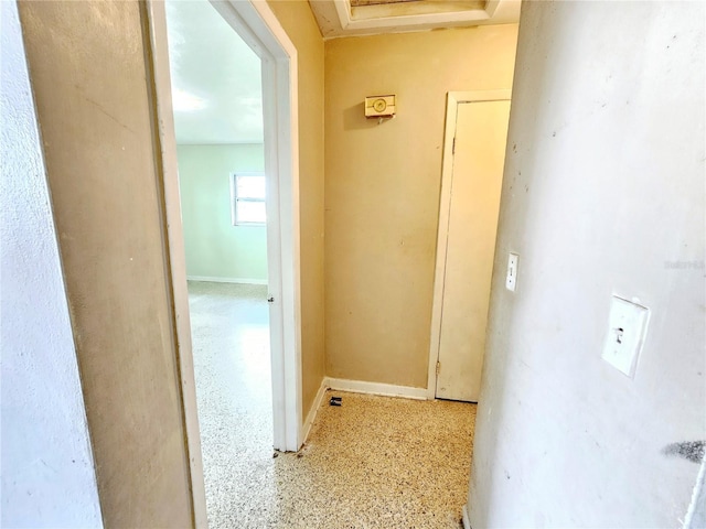 hallway featuring baseboards and speckled floor