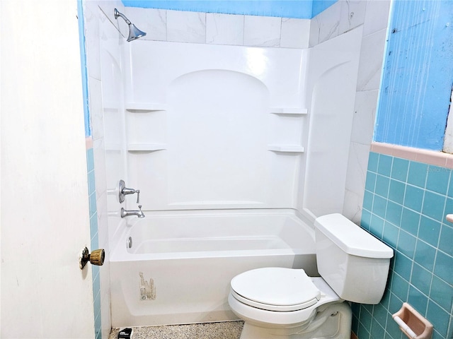 full bathroom featuring toilet, tile walls, washtub / shower combination, and wainscoting