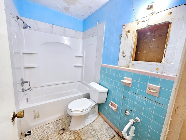 full bathroom featuring tile walls, toilet, speckled floor, shower / bath combination, and wainscoting