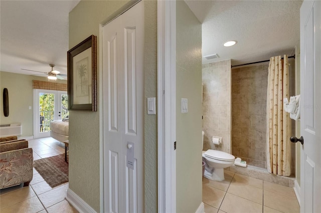 1420 Bayshore Blvd Unit 409, Dunedin, FL 34698 - bathroom with tile patterned flooring, a ceiling fan, a tile shower, toilet, and a textured ceiling