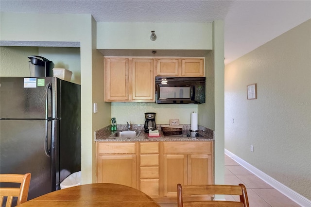 1420 Bayshore Blvd Unit 409, Dunedin, FL 34698 - kitchen with black appliances, light tile patterned floors, a sink, light brown cabinets, and baseboards