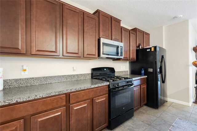 9617 Channing Hill Dr, Ruskin, FL 33573 - kitchen with black appliances, light tile patterned floors, baseboards, and a textured ceiling