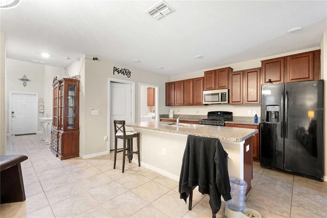 9617 Channing Hill Dr, Ruskin, FL 33573 - kitchen featuring stainless steel microwave, black fridge with ice dispenser, range, a breakfast bar area, and visible vents