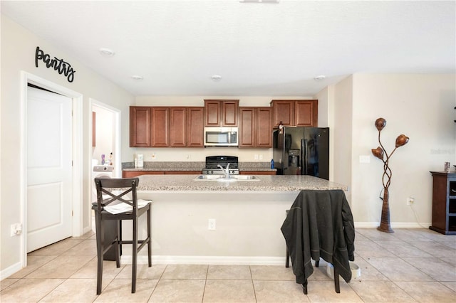 9617 Channing Hill Dr, Ruskin, FL 33573 - kitchen with stainless steel microwave, black fridge with ice dispenser, light countertops, a kitchen bar, and gas stove