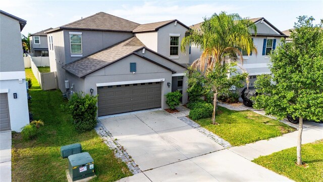 9617 Channing Hill Dr, Ruskin, FL 33573 - view of front of home featuring concrete driveway, roof with shingles, stucco siding, a front lawn, and a garage