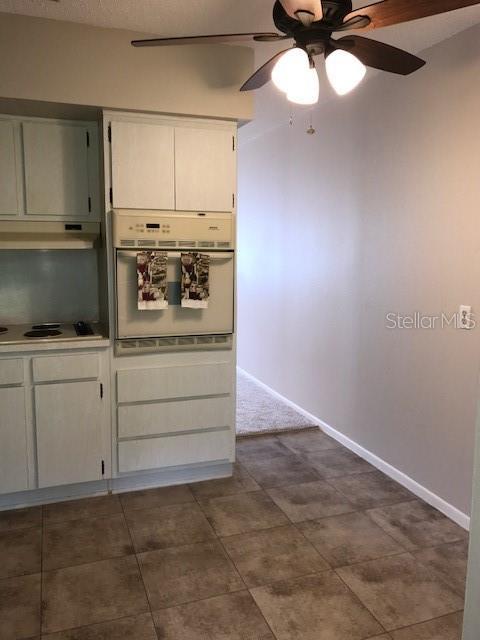 2450 Canadian Way Unit 6, Clearwater, FL 33763 - kitchen featuring white oven, ceiling fan, electric cooktop, under cabinet range hood, and white cabinets