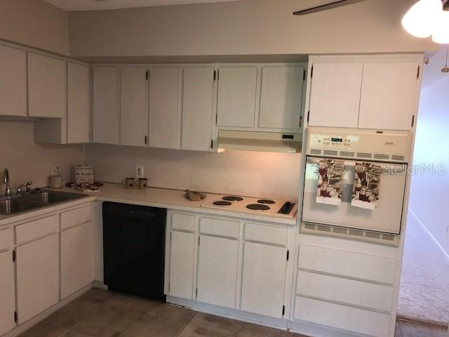 2450 Canadian Way Unit 6, Clearwater, FL 33763 - kitchen featuring white appliances, a sink, under cabinet range hood, and white cabinetry