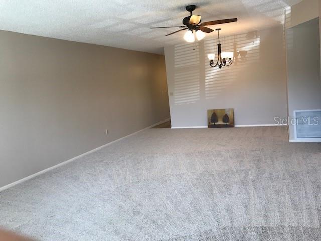 2450 Canadian Way Unit 6, Clearwater, FL 33763 - carpeted spare room featuring a ceiling fan, a chandelier, and baseboards