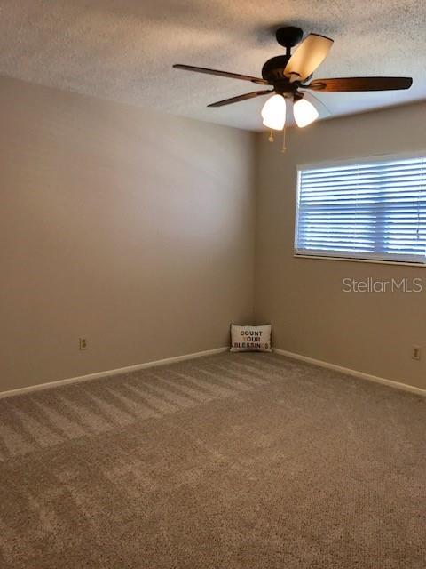 2450 Canadian Way Unit 6, Clearwater, FL 33763 - carpeted spare room featuring a ceiling fan, a textured ceiling, and baseboards