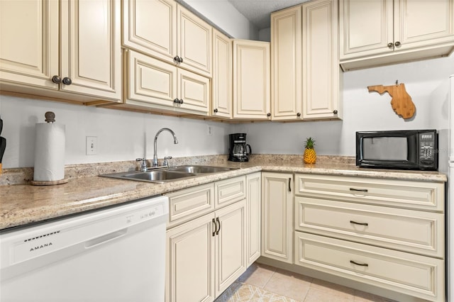 kitchen featuring a sink, black microwave, white dishwasher, light tile patterned flooring, and cream cabinets