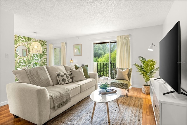 living room with a textured ceiling, baseboards, and light wood-type flooring