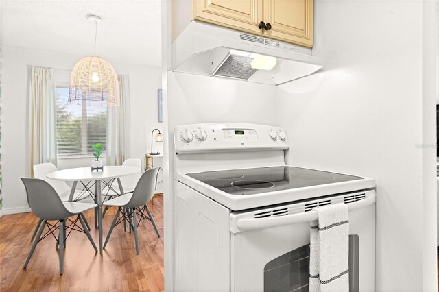 kitchen with electric stove, under cabinet range hood, light wood-type flooring, cream cabinets, and baseboards