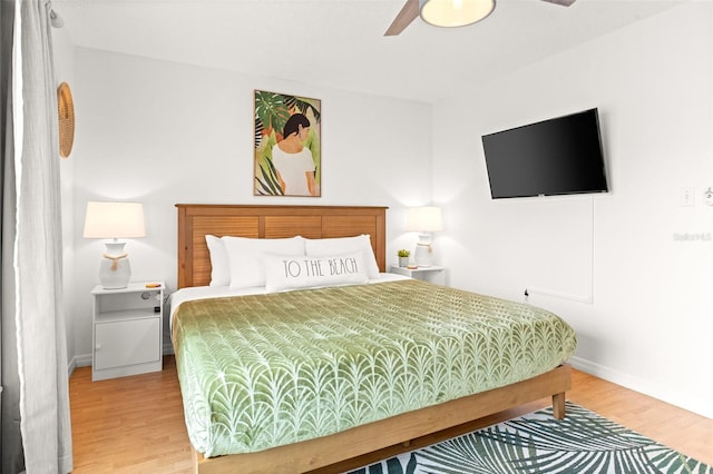 bedroom with a ceiling fan, wood finished floors, and baseboards