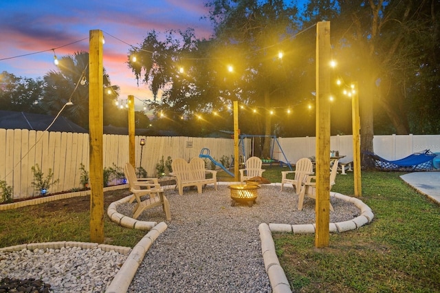 yard at dusk featuring a fenced backyard and a fire pit
