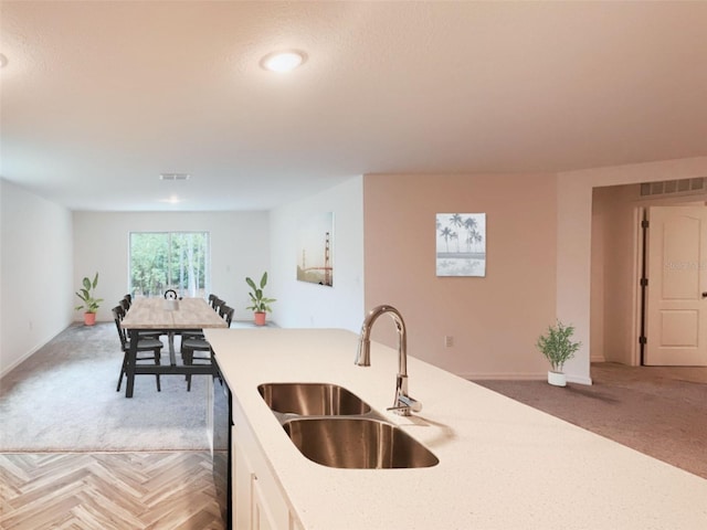 kitchen featuring visible vents, a sink, baseboards, and white cabinetry