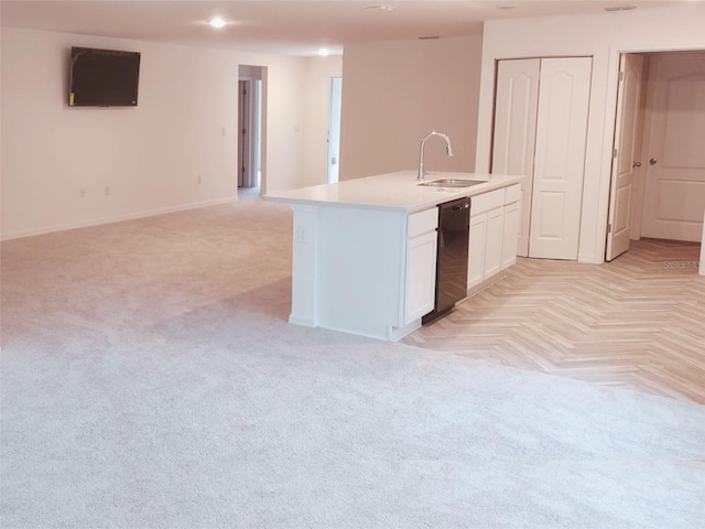 kitchen with a center island with sink, light colored carpet, white cabinets, a sink, and dishwasher