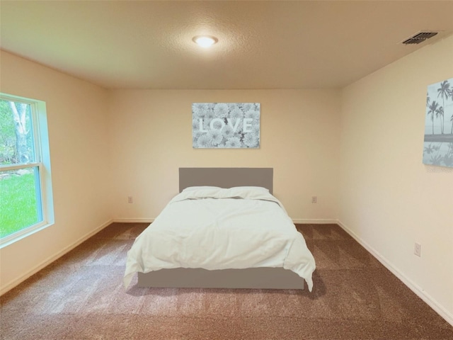 bedroom with multiple windows, dark carpet, and visible vents