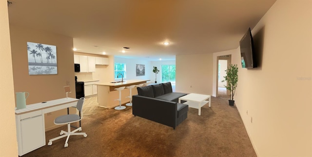 carpeted living area with recessed lighting, baseboards, and a sink