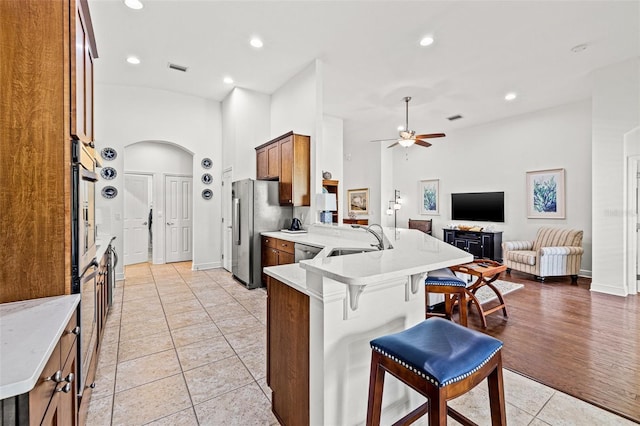kitchen featuring appliances with stainless steel finishes, a sink, light tile patterned floors, a peninsula, and open floor plan
