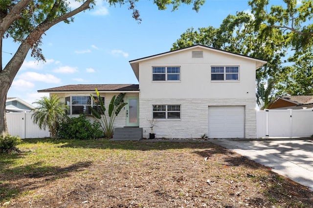 split level home featuring fence, a gate, concrete driveway, and a garage
