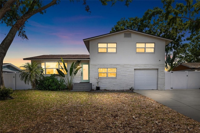 view of front facade with driveway, stone siding, an attached garage, and fence