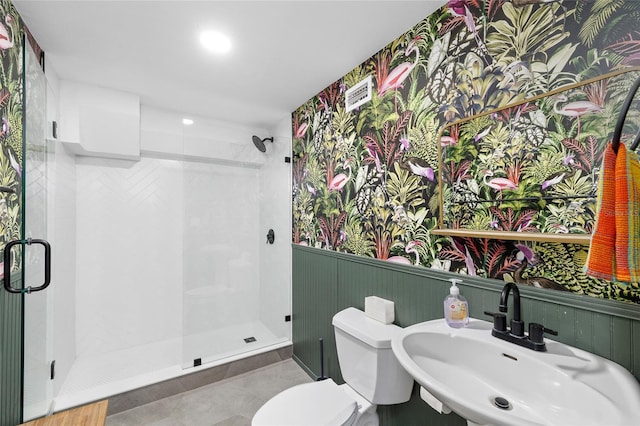 full bathroom featuring a sink, a wainscoted wall, a stall shower, toilet, and tile patterned flooring