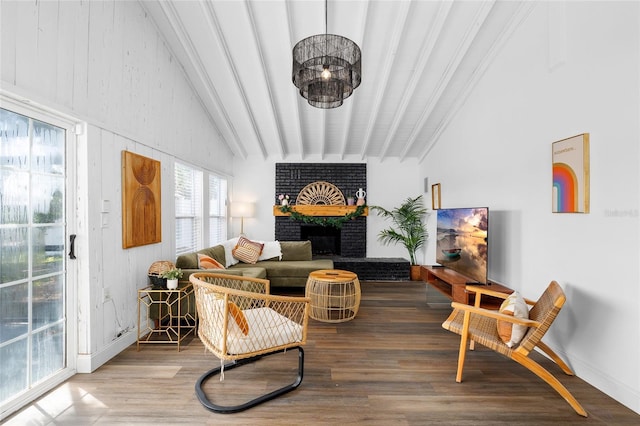 living area featuring baseboards, lofted ceiling with beams, wood finished floors, and a brick fireplace