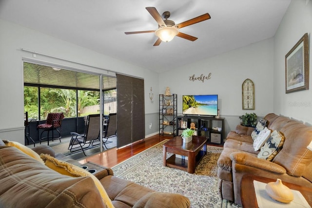 living room featuring ceiling fan, wood finished floors, and vaulted ceiling