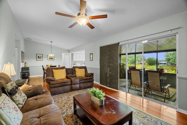 living room with baseboards, ceiling fan, wood finished floors, and vaulted ceiling
