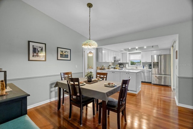 dining area featuring baseboards, lofted ceiling, and wood finished floors